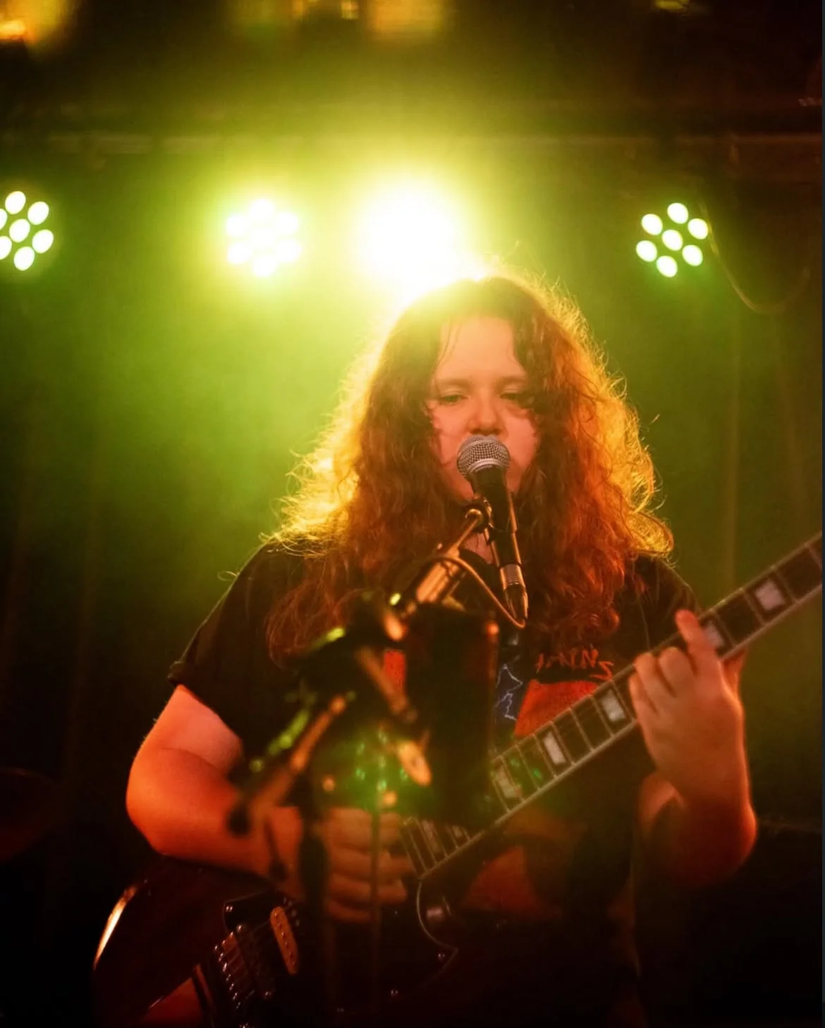 Mia singing and playing guitar on stage